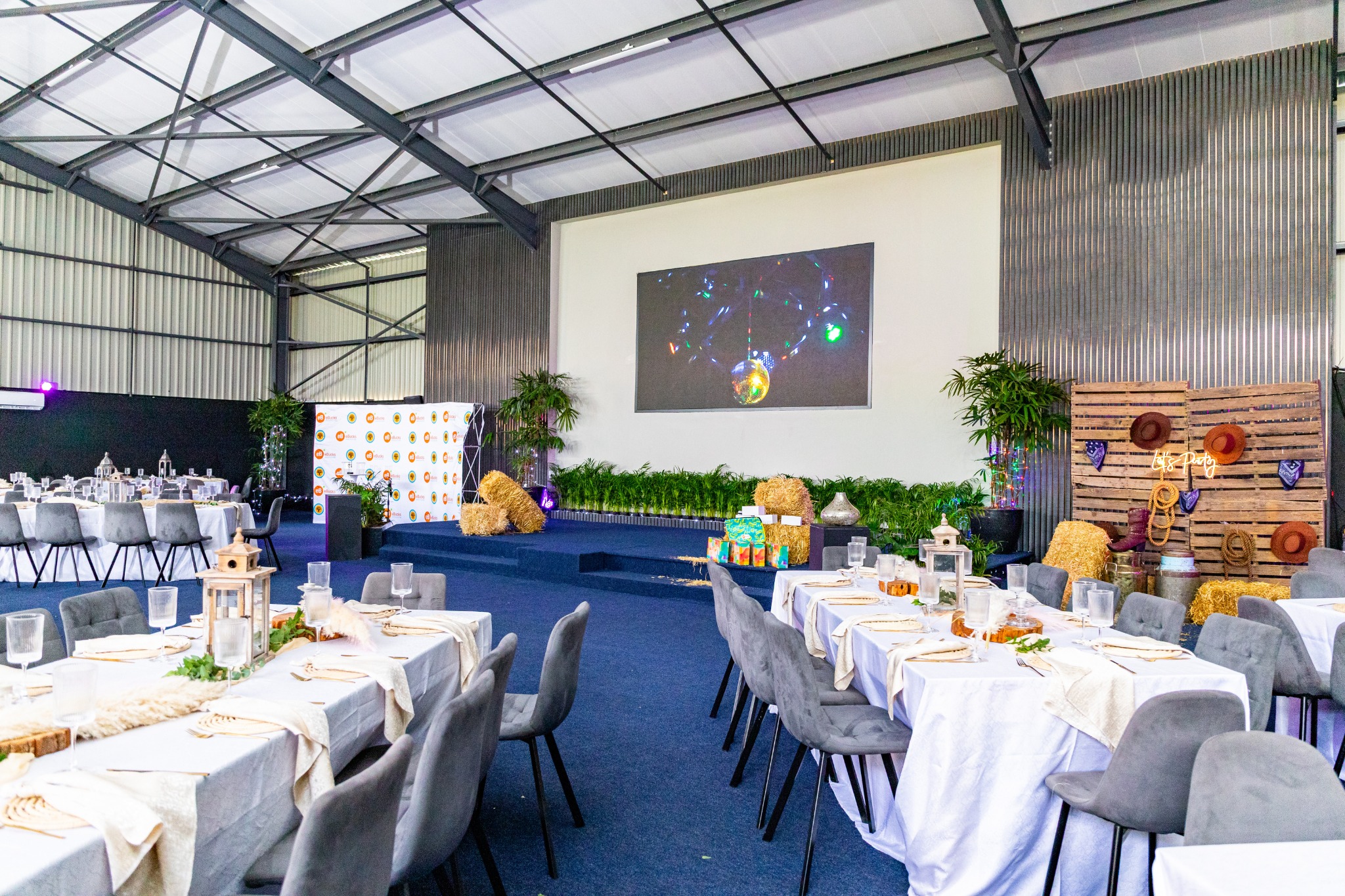 Long banquet tables and presentation screen set for a conference dinner at Apple Blossom Hotel, Venue & Spa, Johannesburg